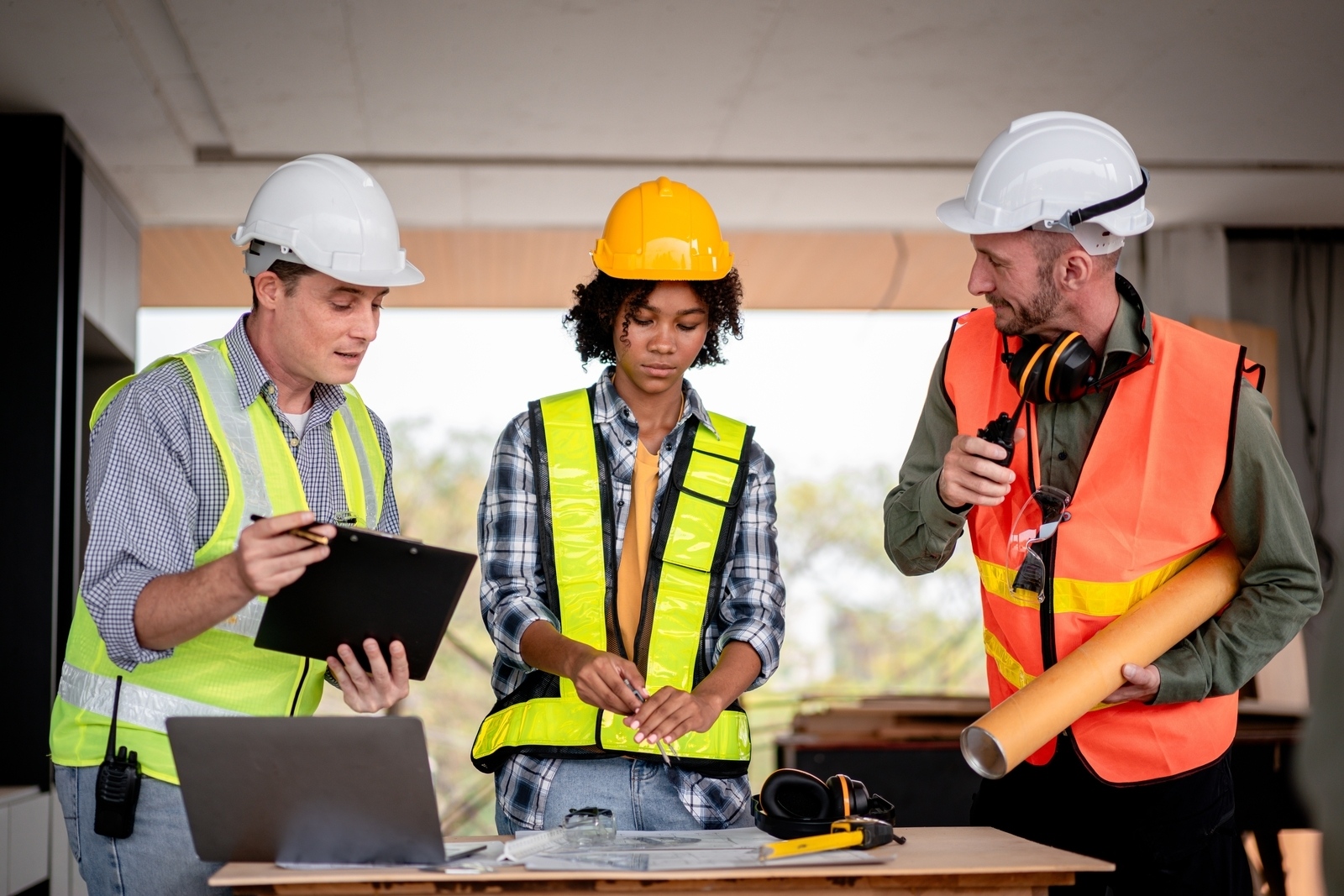 Threeconstructionworkersarestandingaroundatablewitha