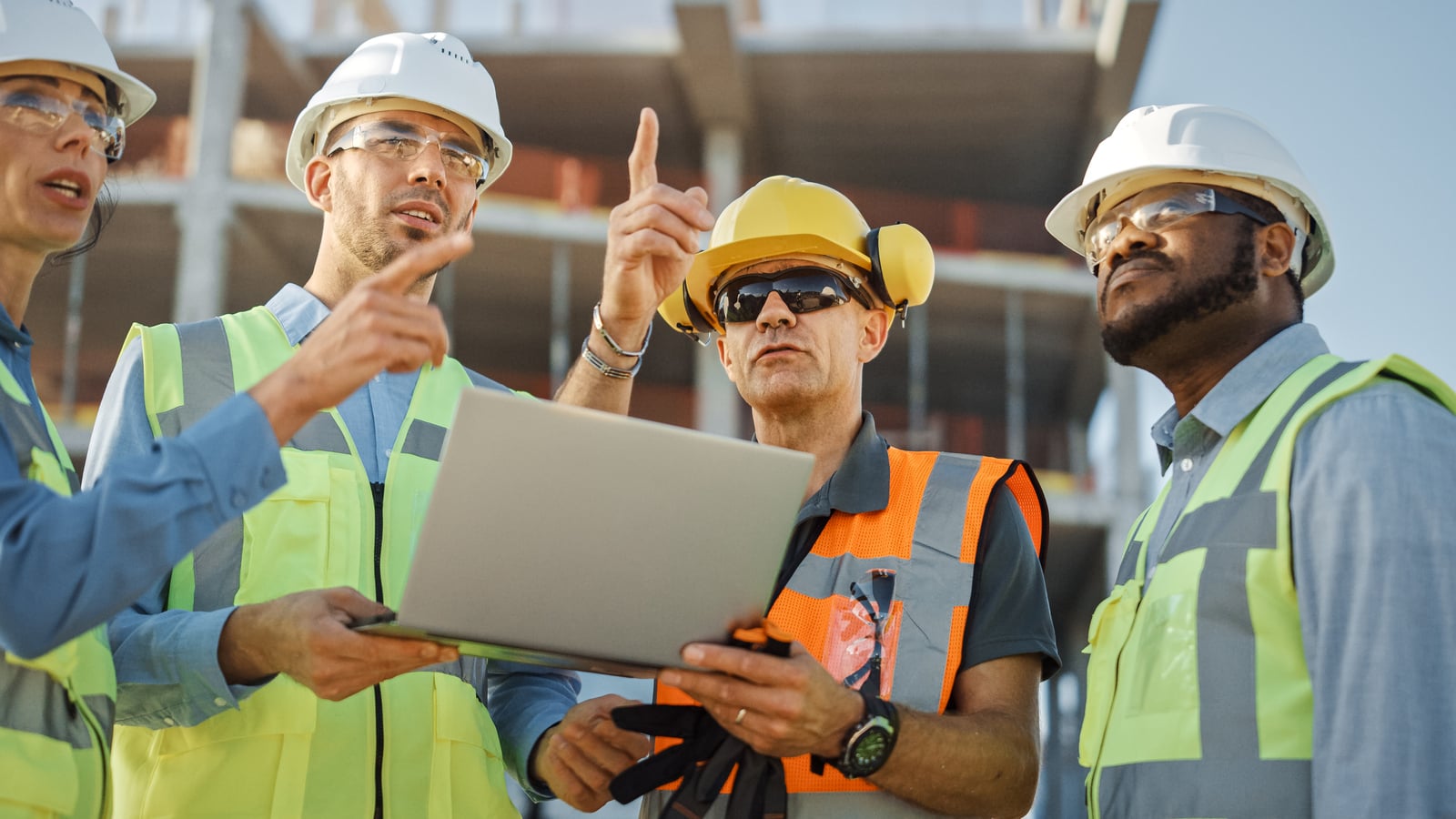 Diverseteamofspecialistsuselaptopcomputeronconstructionsite