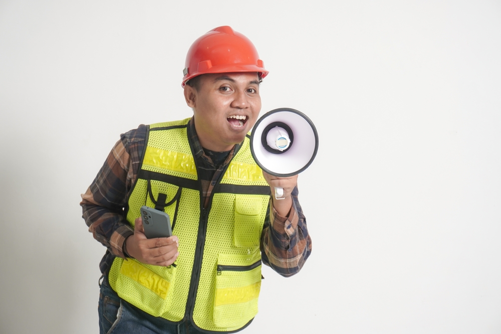 Asianconstructionworkerwearingsafetyvestandhelmetholdinga | construction spike Asianconstructionworkerwearingsafetyvestandhelmetholdinga
