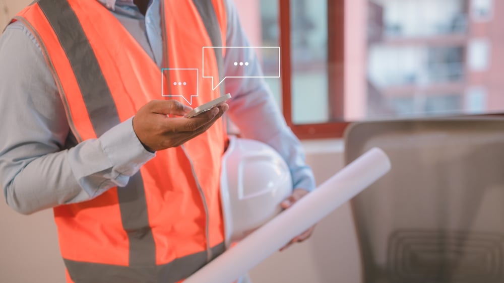 Socialmediaanengineerworkingonsiteusingsmartphonetyping | construction spike Socialmediaanengineerworkingonsiteusingsmartphonetyping