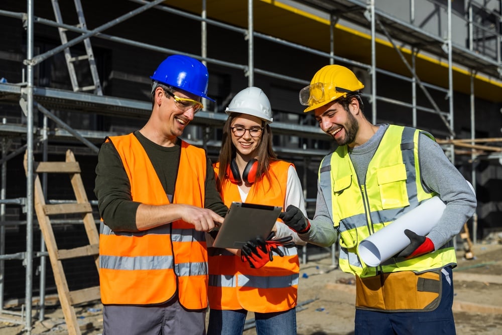 Threediverseengineersdiscussingconstructionplansonadigitaltablet